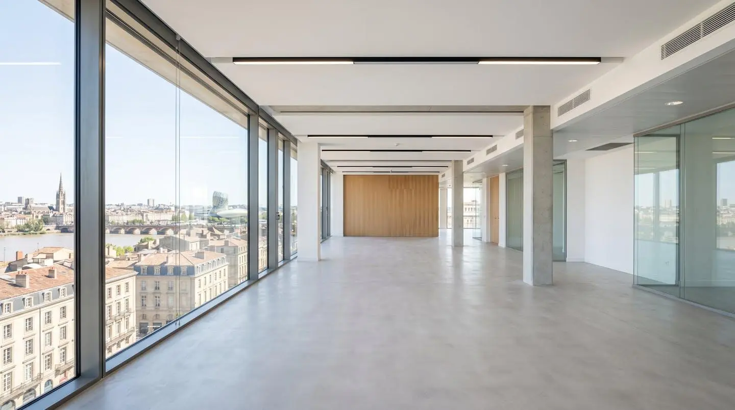 Bureau moderne et lumineux vide avec grande fenêtre donnant sur l'architecture bordelaise reconnaissable, lumière naturelle abondante traversant l'espace contemporain